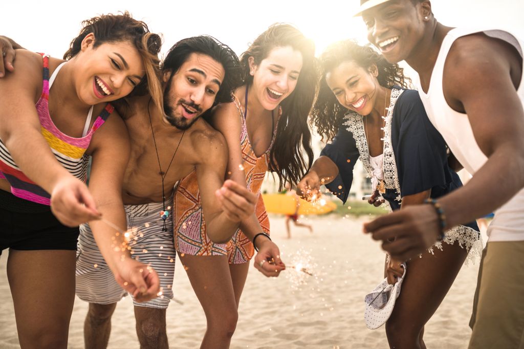 friends using a sparkler togetherness on the beach