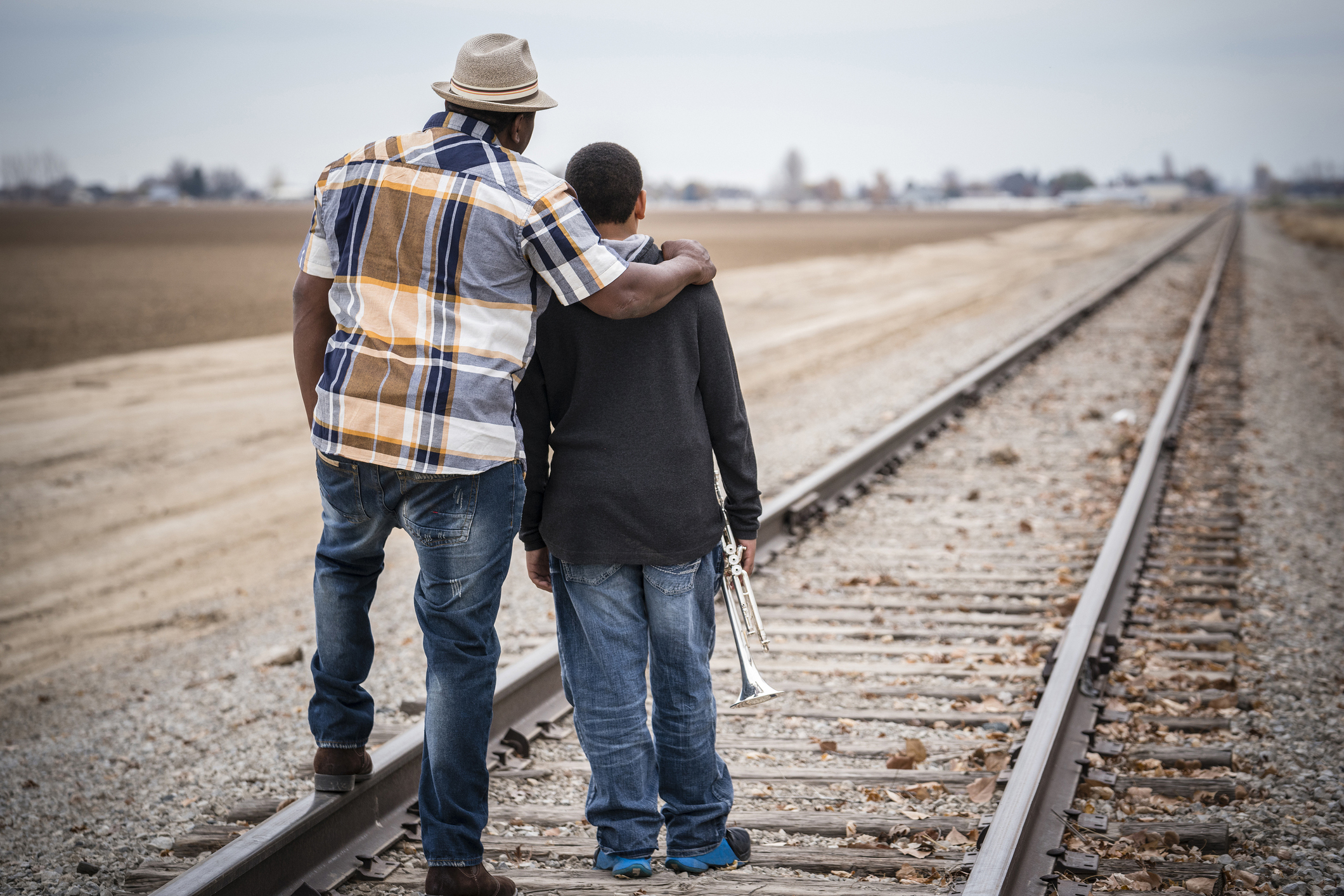 Father and son standing on train track with trumpet