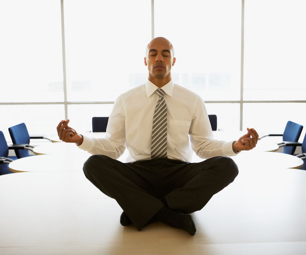Businessman Meditating on Conference Table