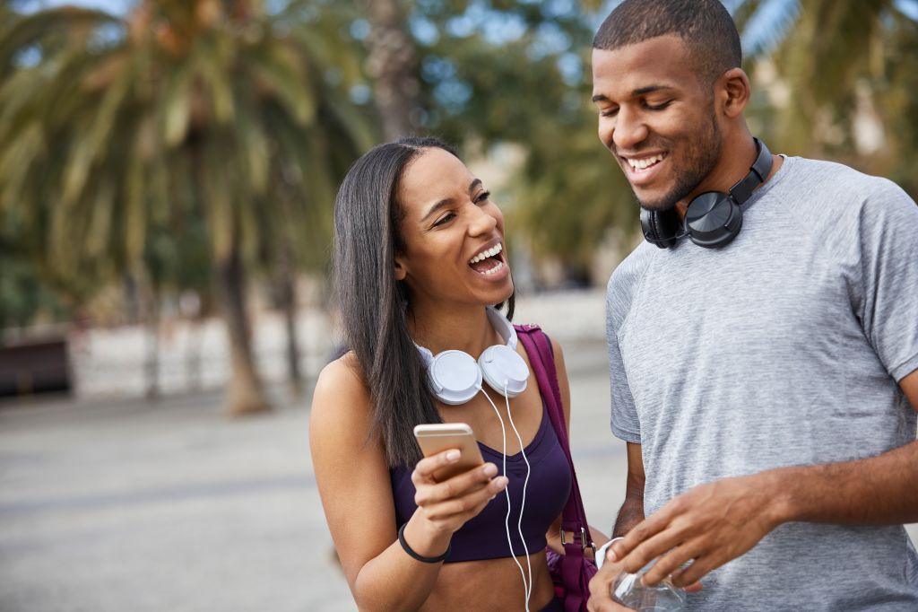 Cheerful couple looking at smart phone in park