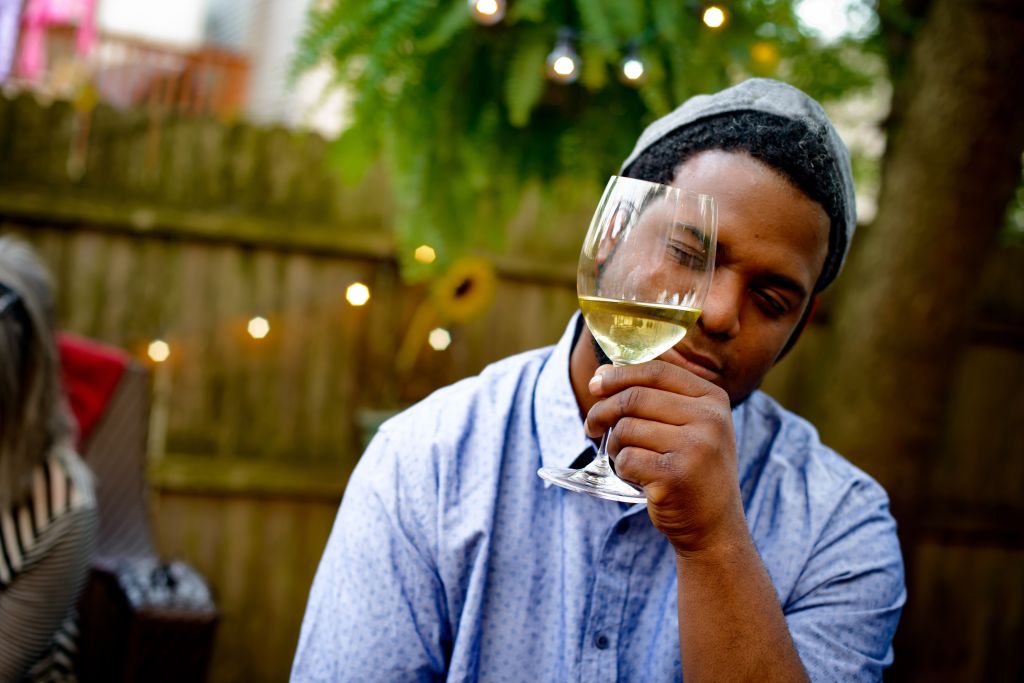 Man at garden party, holding wine glass, inspecting wine