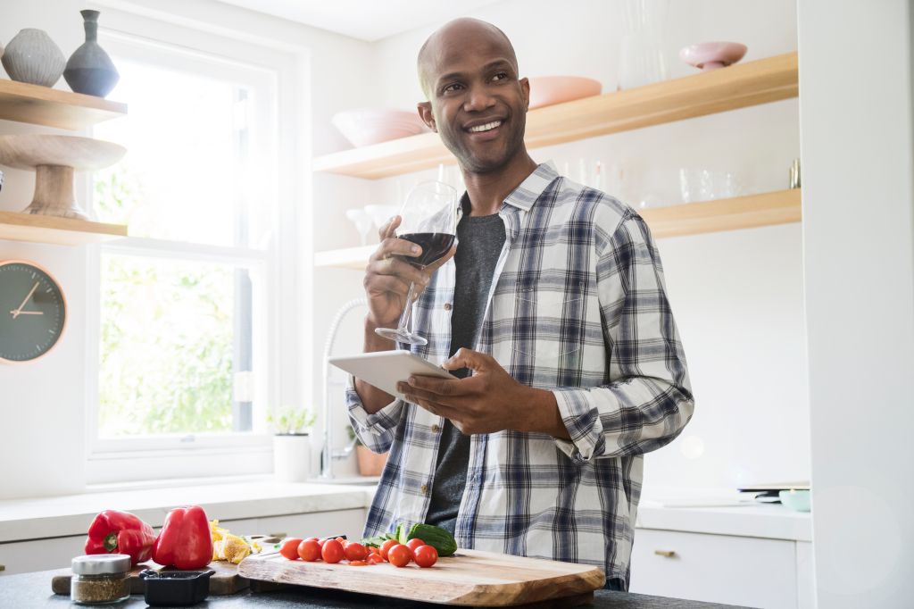 Man having wine while using tablet PC in kitchen