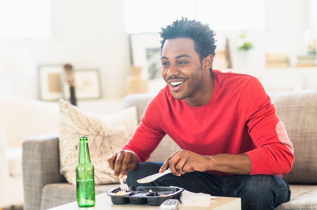 Man eating dinner and watching television
