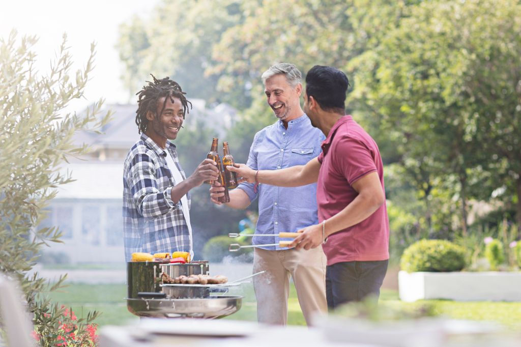 Happy male friends raising toast with beer bottles