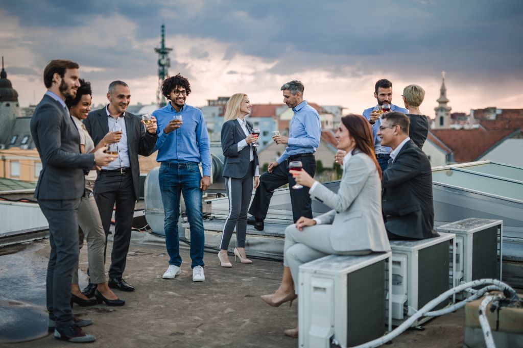 Large group of happy business colleagues talking on a rooftop party.