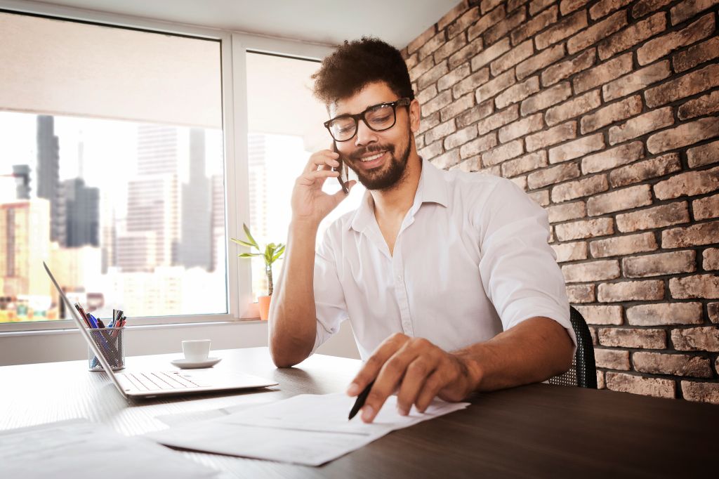 African man checking document with client talking on smart phone