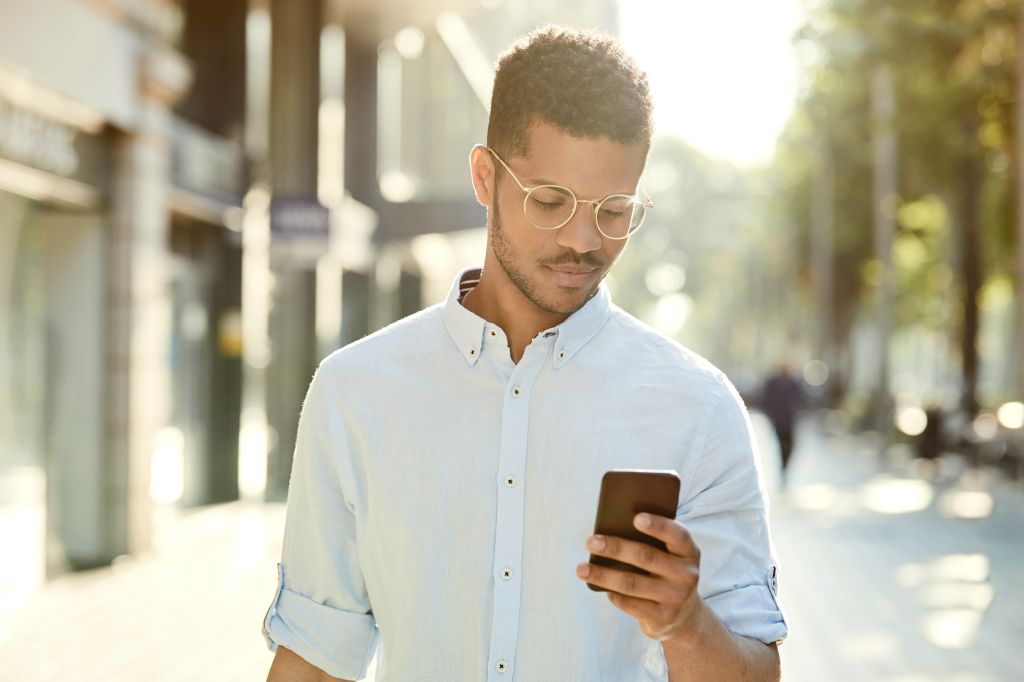 Young man using mobile phone on sidewalk in city