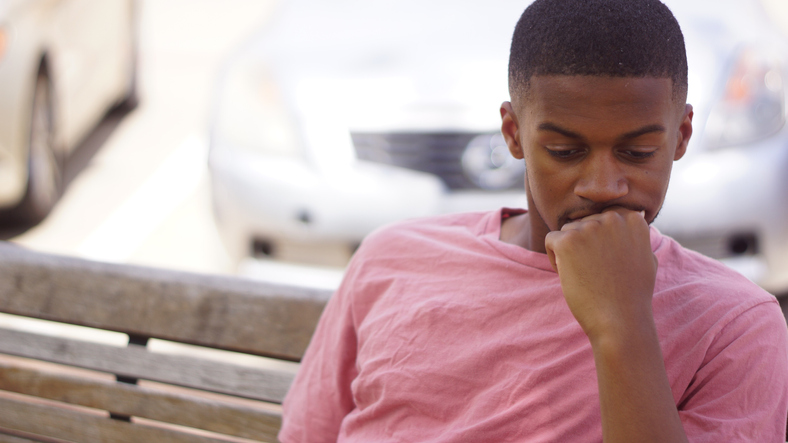 Close-Up Of Thoughtful Man Sitting On Bench