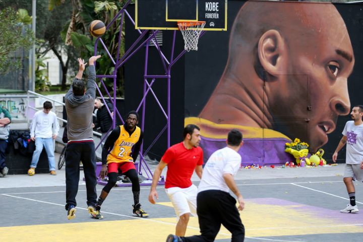 A group of boys play basketball, in the basketball court...