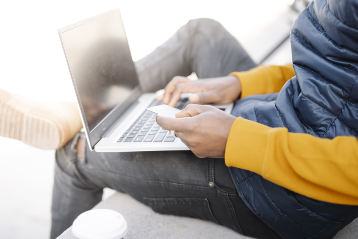 Close-up of man using laptop and credit card for online shopping