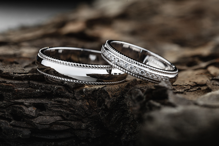 Pair of stylish silver wedding rings on wood background