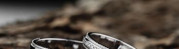 Pair of stylish silver wedding rings on wood background