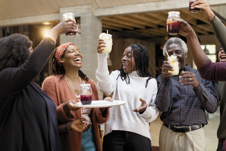 Enthusiastic multi-generation family toasting lemonade and sangria on patio