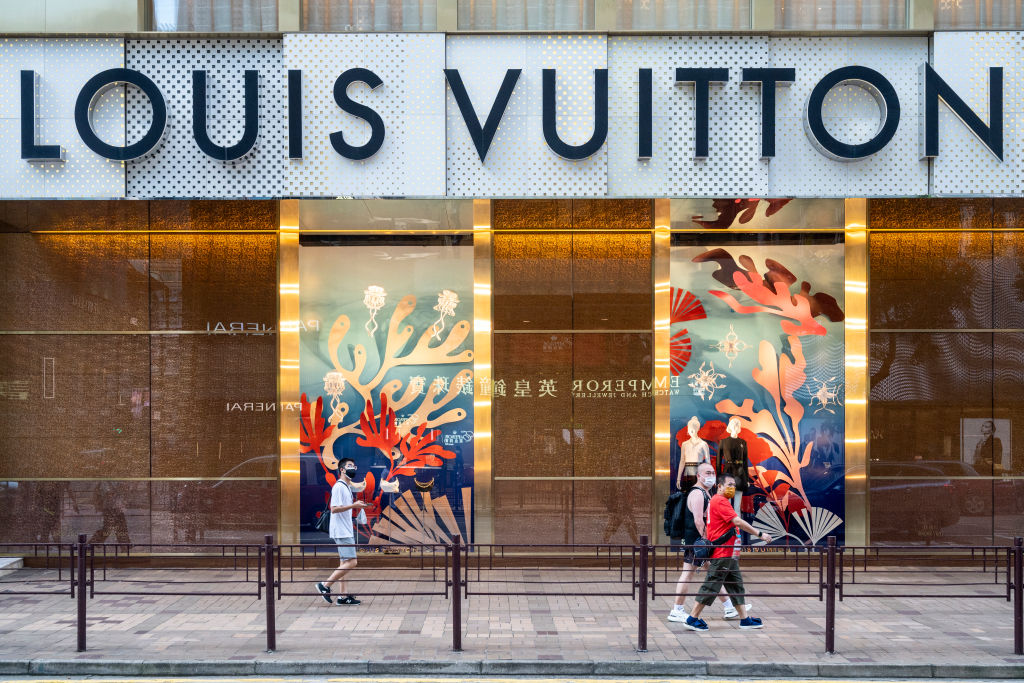 Shoppers walk past the French luxury fashion brand Louis...