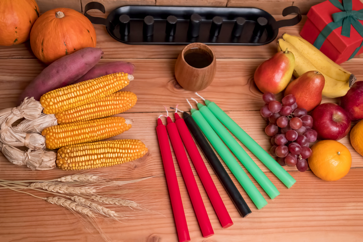 Kwanzaa holiday concept with decorate seven candles red, black and green, gift box, pumpkin,corn and fruit on wooden desk and background.