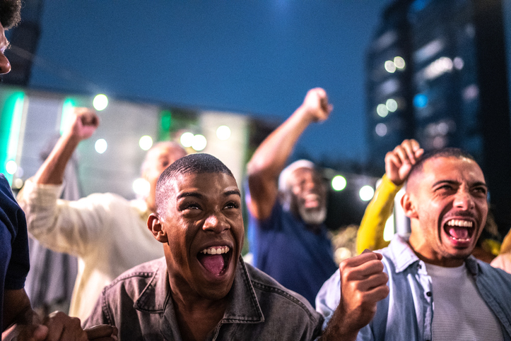 Sports fans watching a match and celebrating at a bar rooftop