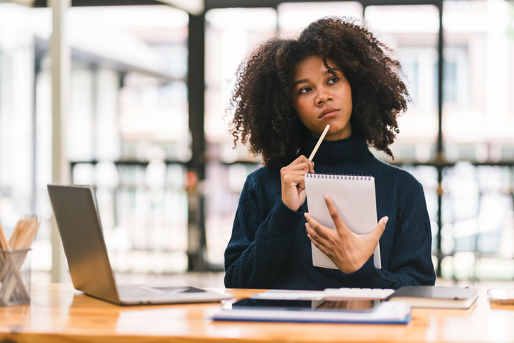 African American businesswoman or accountant with afro hair using a calculator, graphs, and charts to analyze market data, balance sheets, accounts, and net profits.