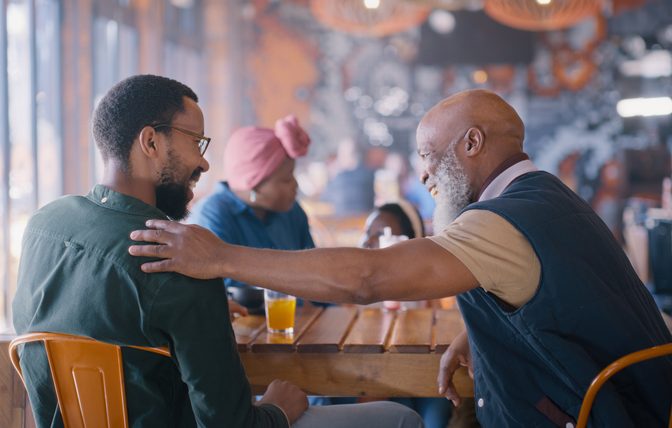 Senior father, man and restaurant with family, dinner and embrace with conversation, memory and bonding. Elderly dad, son and African people with love, chat and happy together in diner for reunion