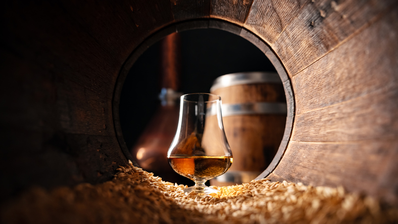 Glass of whiskey in an old wooden oak barrel