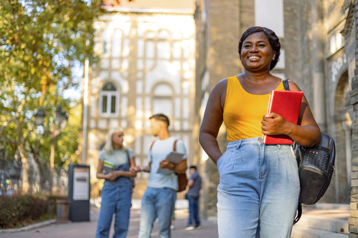Smiling student holding notebook on university campus