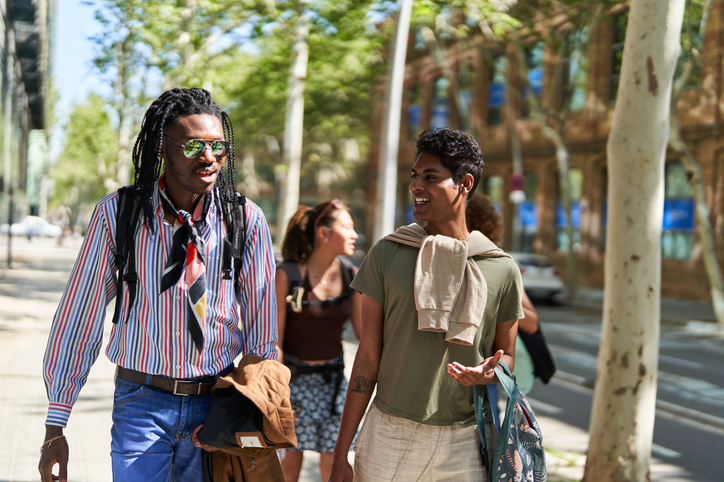 Group of young multiethnic friends walking and chatting on a sunny city sidewalk