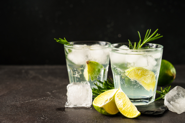 Gin tonic with gin, tonic, ice cubes, lime and rosemary.