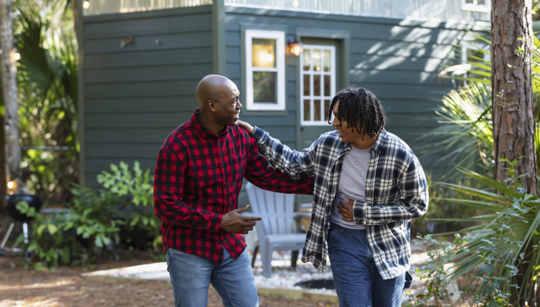 Father and teenage son conversing in back yard