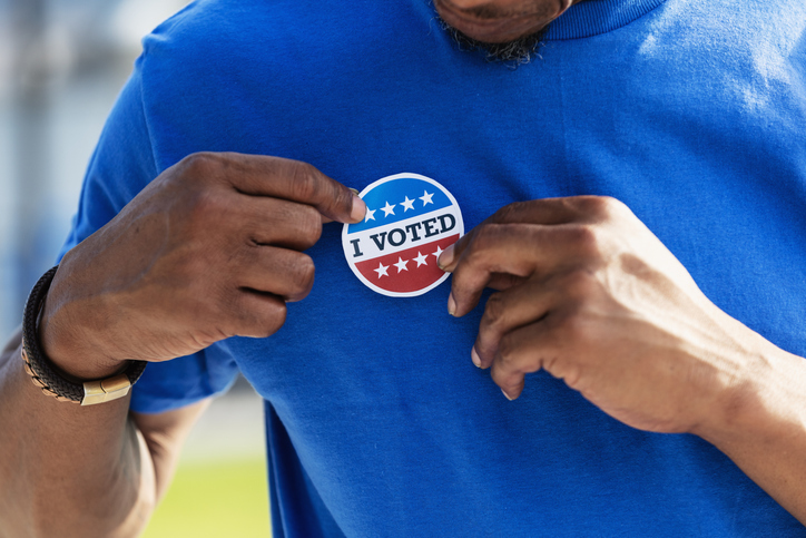 Cropped view of man putting I Voted sticker on shirt