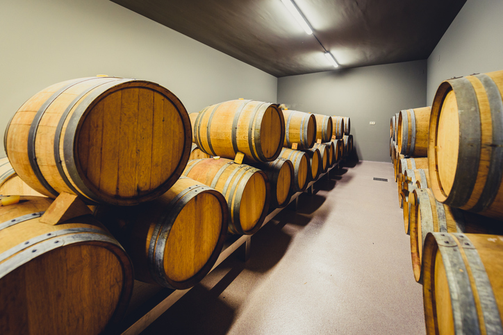 Wooden wine barrels stacked in modern winery cellar in Spain.