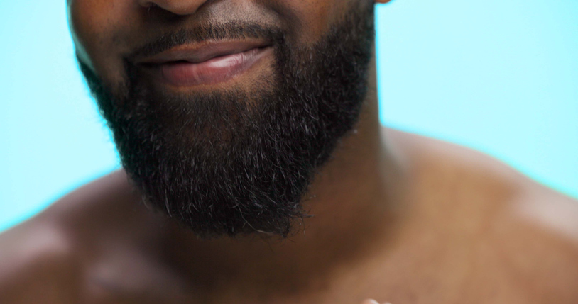 Beard, beauty and mouth of black man on blue background for morning skincare routine. Grooming, masculinity and self care with person closeup in studio for personal hygiene, relax or wellness