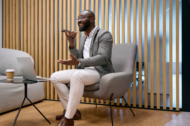 Professional businessman talking on speakerphone in office lounge