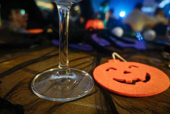 A glass of white wine and a handmade felt pumpkin on a table at the Halloween party